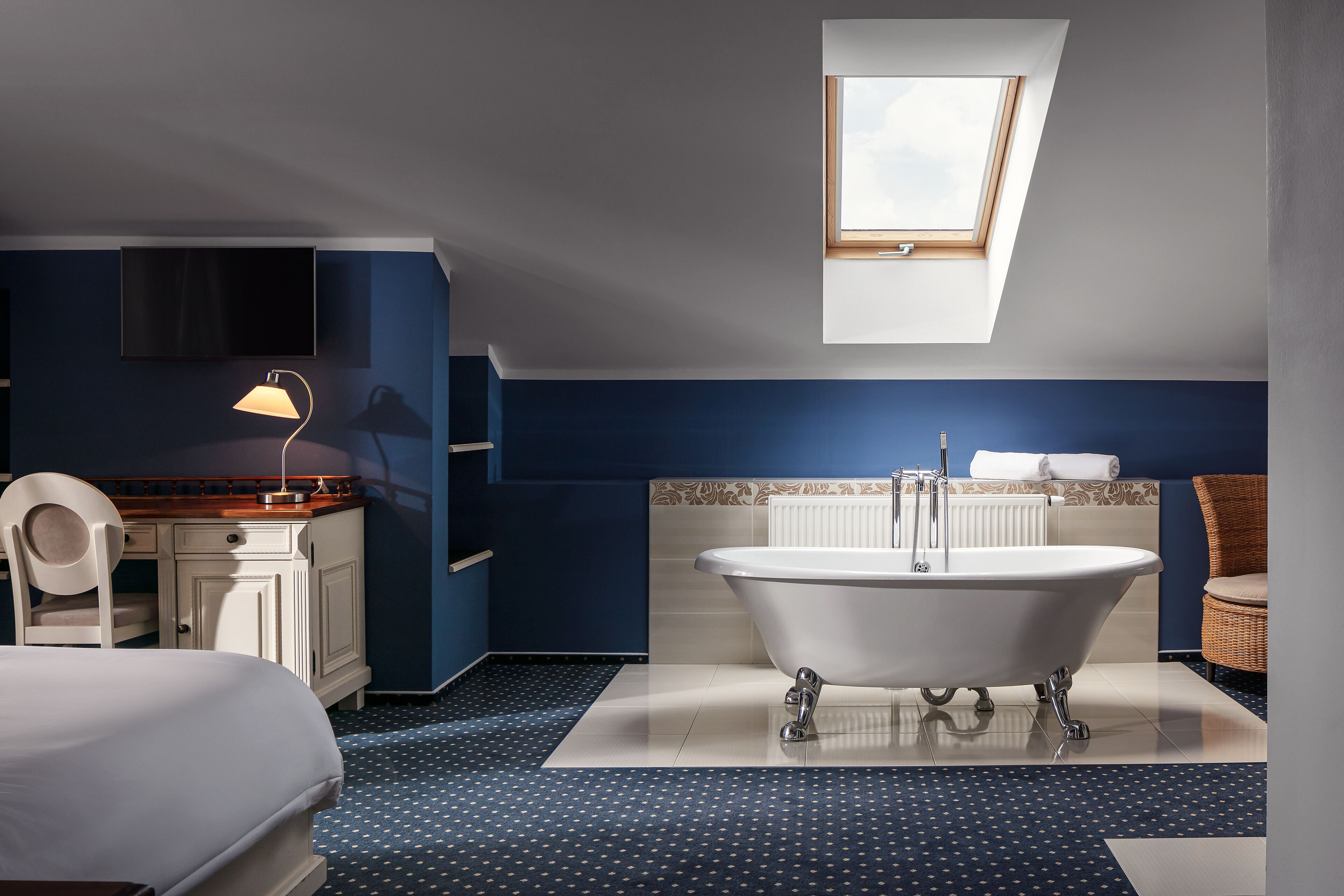 A modern bathroom with a freestanding bathtub, a vanity with a mirror, and a skylight above the bathtub.