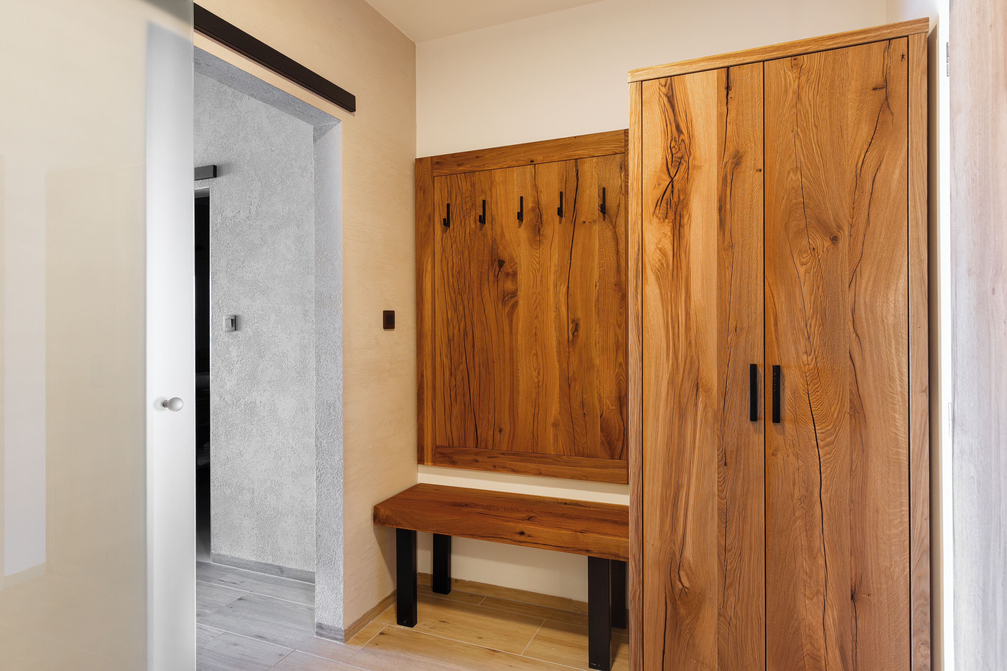 Um corredor com um banco de madeira e um guarda-roupa com várias portas.