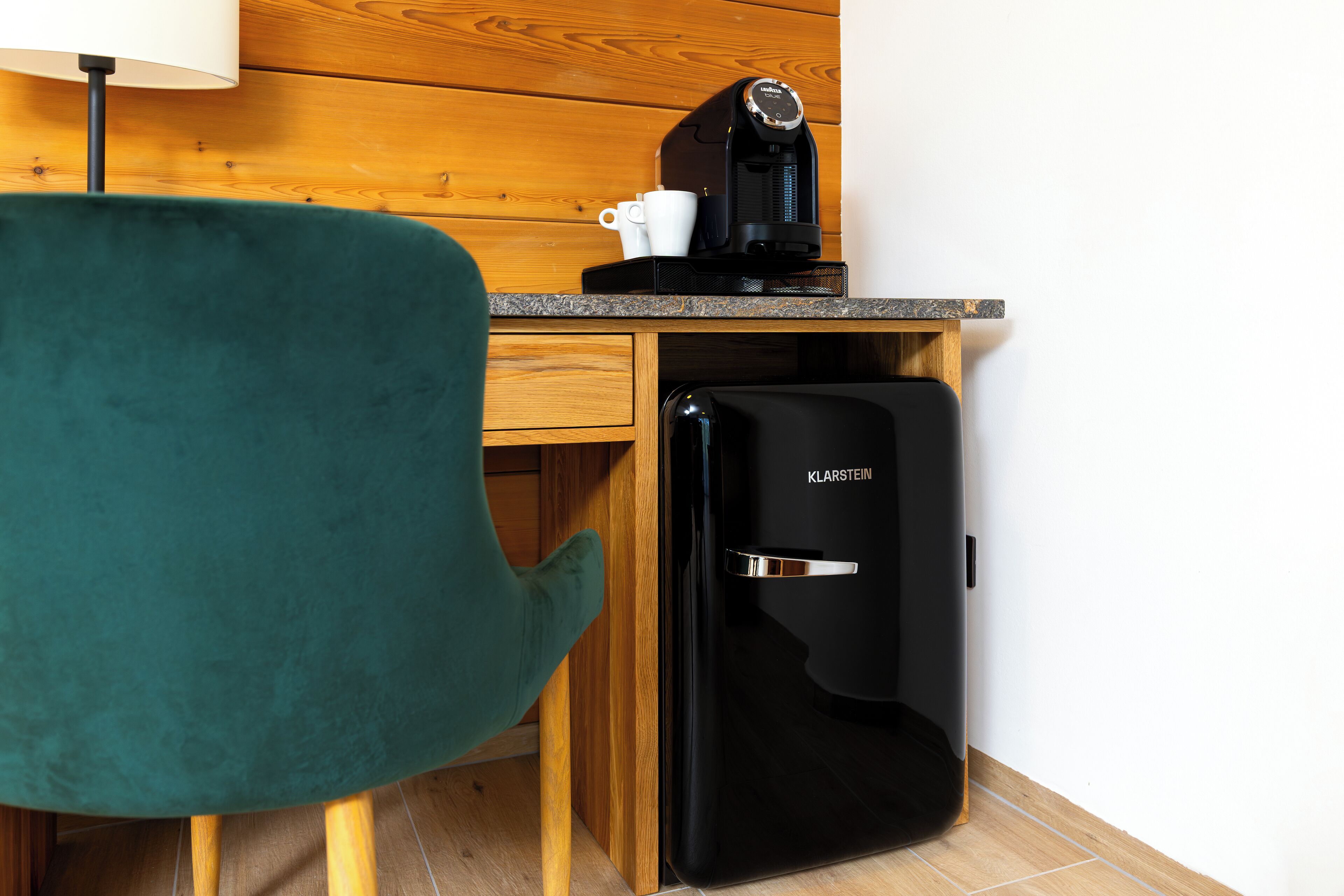 Una kitchenette compacta con cafetera, una taza y refrigerador.