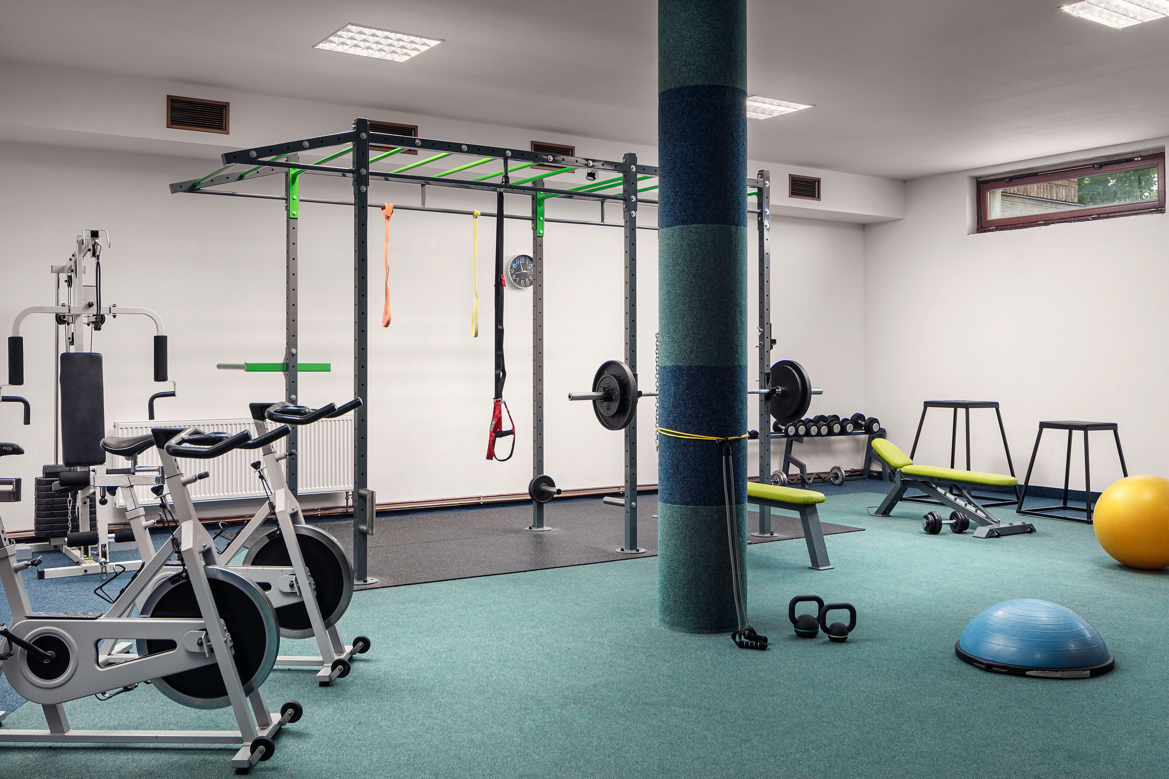 Een sportschool met fitnessapparatuur, een pull-up stang en een grote trainingsbal.