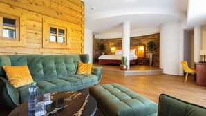 Una habitación de hotel moderna con un sofá verde, una mesa de centro redonda y una pared decorativa de madera.