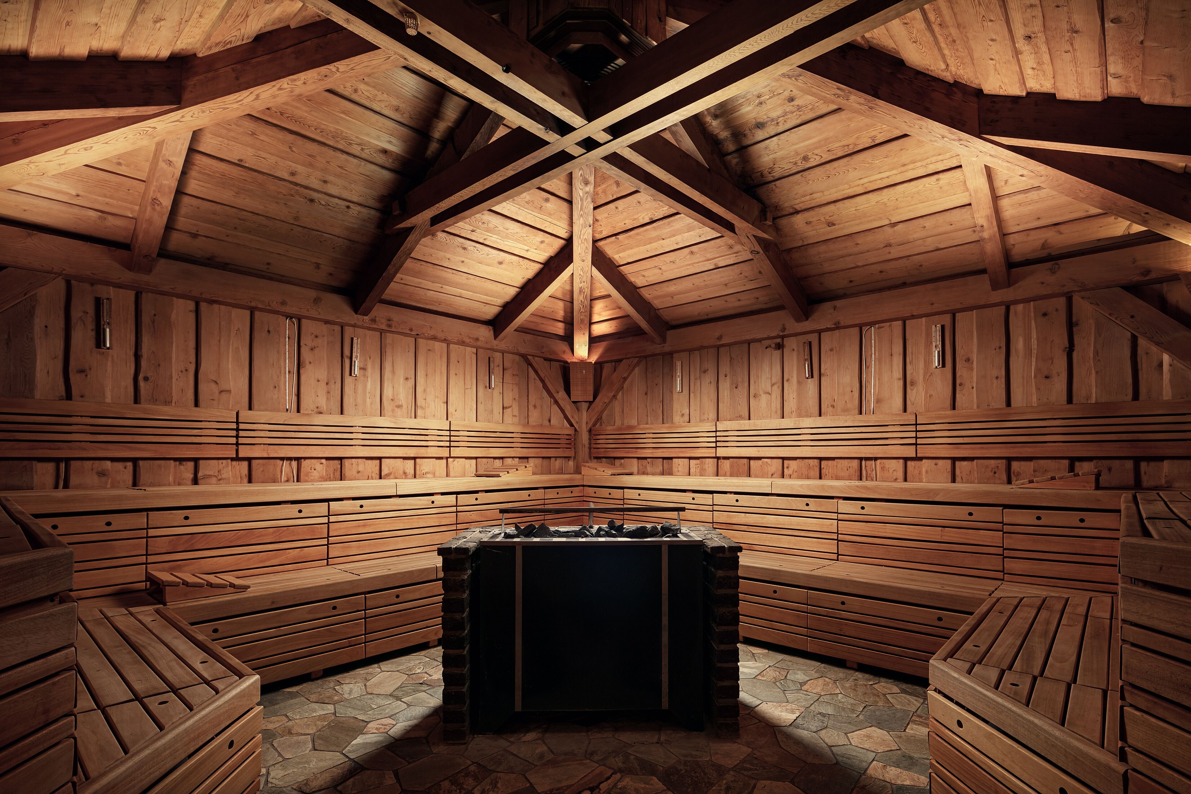 A sauna with wooden benches and a central heating unit.