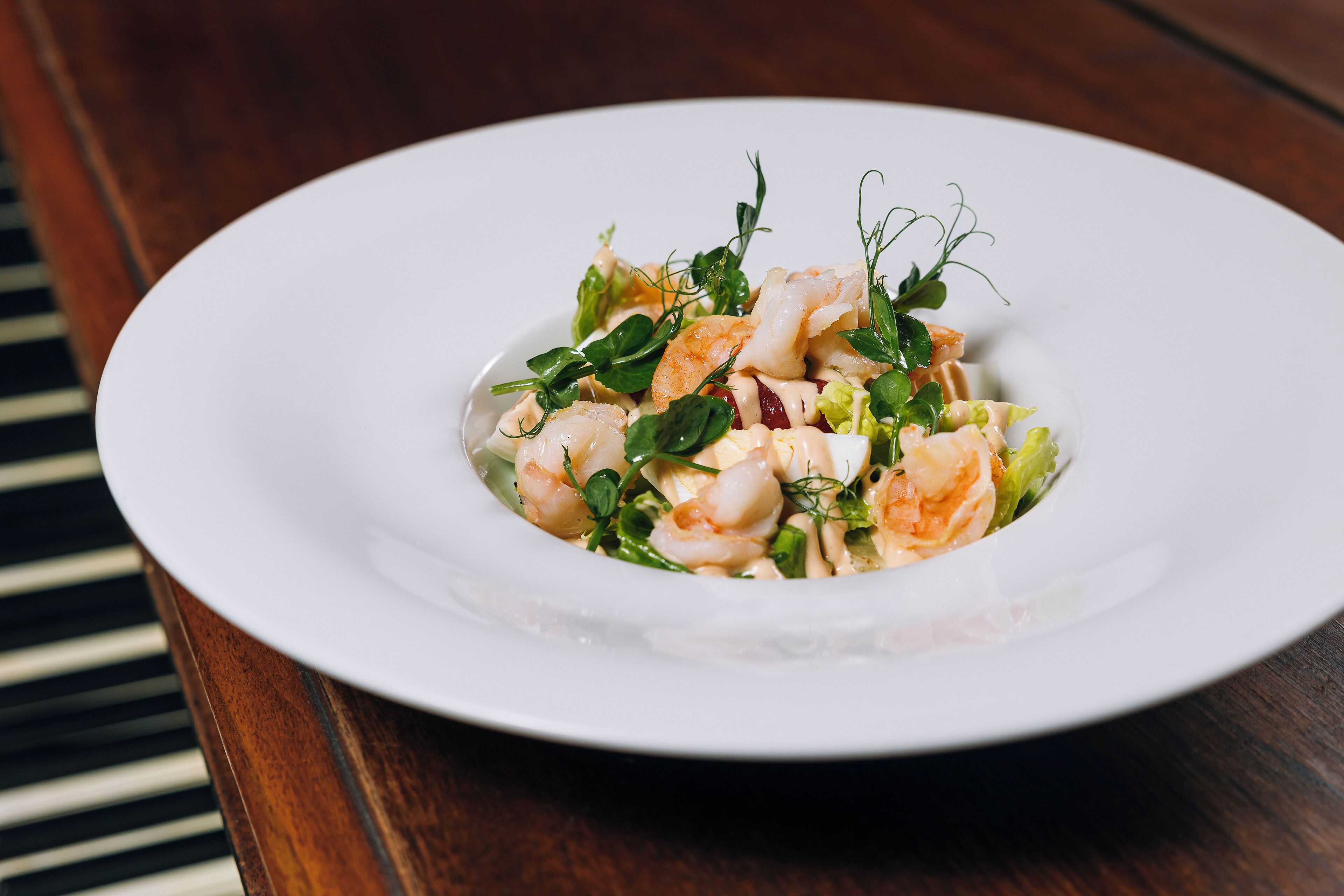 A white plate with a seafood dish on a wooden table.