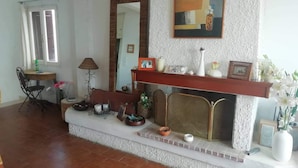 A living room with a fireplace, a dining area with a table and chairs, and a large mirror on the wall. - Nice House With sea View in Spetses, Greece (Spetses)