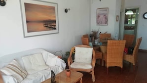 A living room with a sofa, a coffee table, and a dining area with chairs and a table. - Nice House With sea View in Spetses, Greece (Spetses)