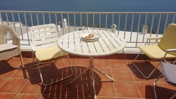 A terrace with a round table and two chairs, overlooking a body of water and distant land. - Nice House With sea View in Spetses, Greece (Spetses)