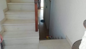 A staircase leading to a door with a small window. There are a few items on the floor near the door. - Nice House With sea View in Spetses, Greece (Spetses)