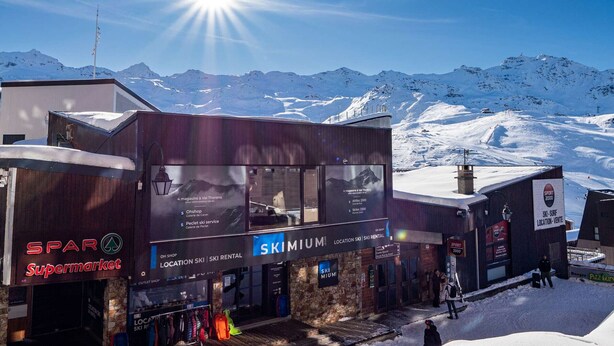 Een winkel voor het verhuren van ski's, SKIMIUM geheten, met een bord waarop staat 'LOCATIE SKI VERHUUR'.