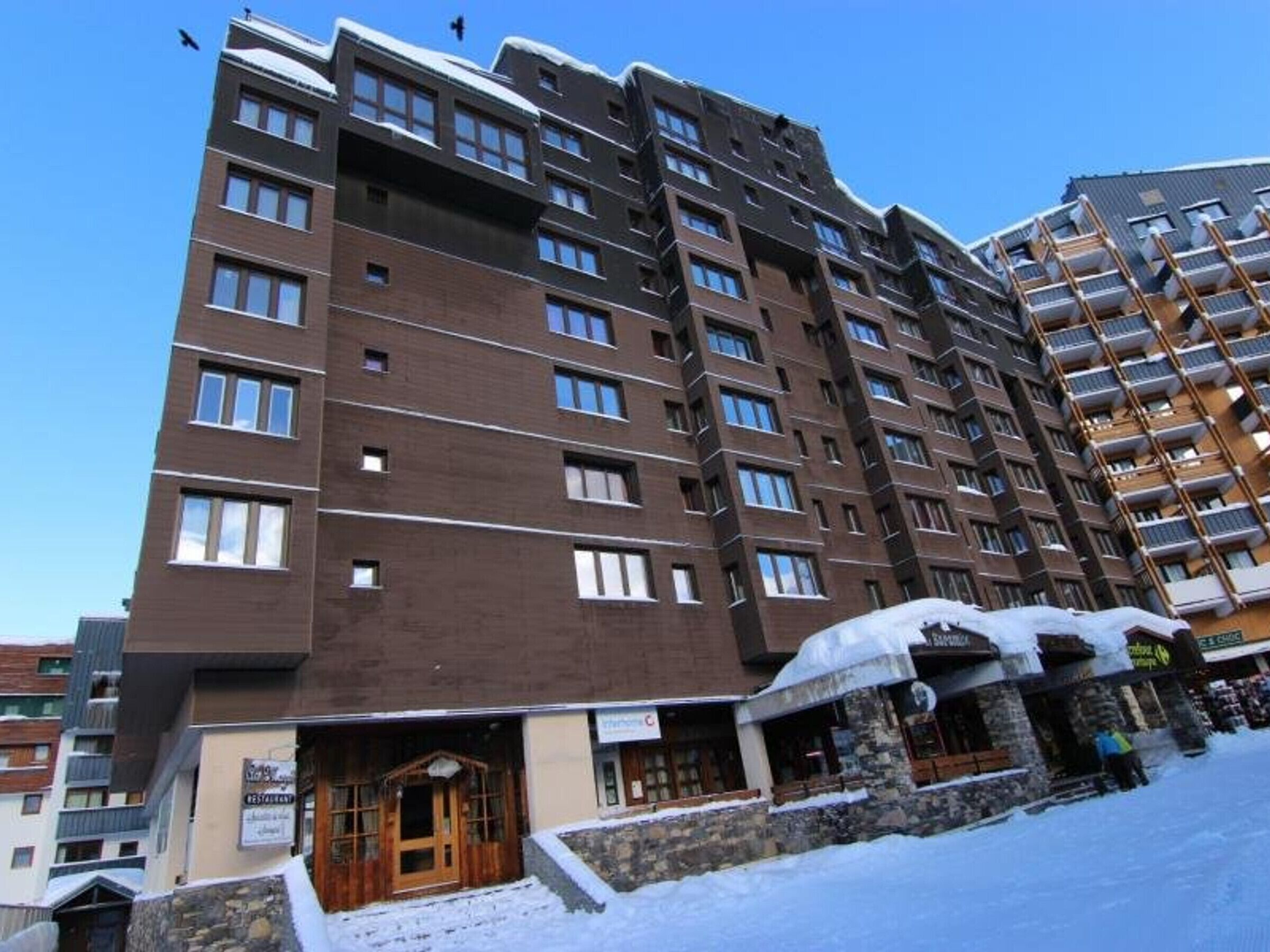 A multi-story hotel with a stone facade and a snow-covered entrance.