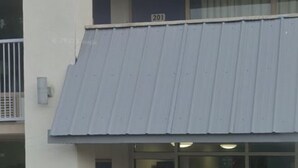 A building with a blue awning, a visible door, and a window with a reflection. - Rodeway Inn Asheboro (Asheboro)