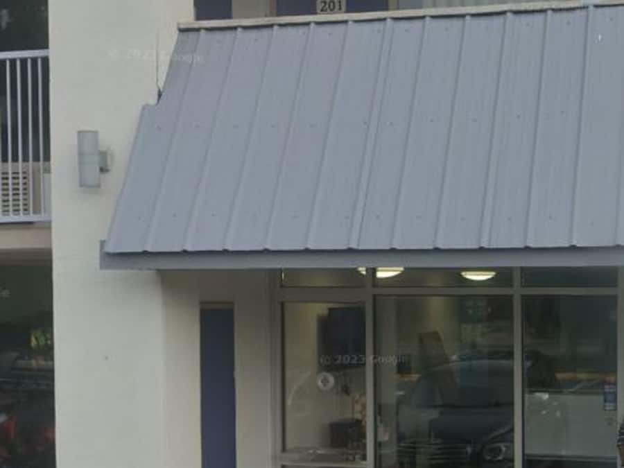 A building with a blue awning, a visible door, and a window with a reflection.