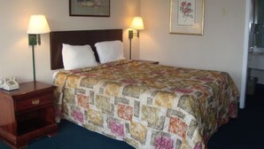 Habitación de hotel con cama, dos lámparas de noche, una mesita de noche y un cuadro en la pared.