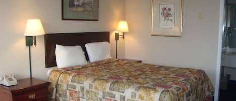 A hotel room with a bed, two bedside lamps, a nightstand, and a framed picture on the wall.