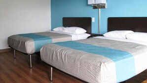 Two twin beds with grey and blue bedding, a wooden floor, and a wall-mounted lamp. - Rodeway Inn Asheboro (Asheboro)