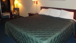 Habitación de hotel con una cama grande, dos lámparas de noche, una silla, un escritorio y un cuadro en la pared.