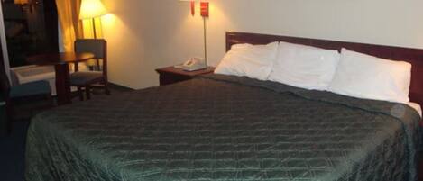 A hotel room with a large bed, two bedside lamps, a chair, a desk, and a painting on the wall.