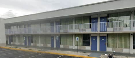 Un motel con aparcamiento y una moto estacionada al frente.