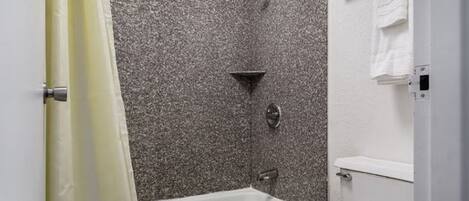 A bathroom with a bathtub, shower, and toilet.
