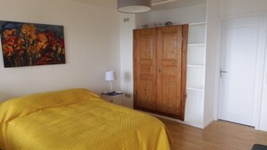 A bedroom with a large bed, a wardrobe, a painting on the wall, and a lamp.