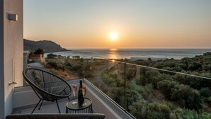 A balcony with a view of the sunset over the sea, a bottle of champagne, and two glasses on a small table. - Magnificent Brand New Villa in Sfinari (Chania)
