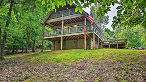 A wooden cabin with a balcony, surrounded by trees and a flag. - Golfer's Retreat at Kudzu Cove Cabins Resort (Guntersville)