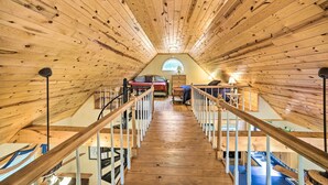 A wooden interior with a central staircase, a small window at the end, and a bed with a red blanket. - Golfer's Retreat at Kudzu Cove Cabins Resort (Guntersville)