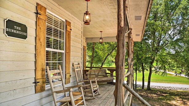Une véranda en bois avec des fauteuils à bascule et une pancarte indiquant : « The Bunkhouse ».