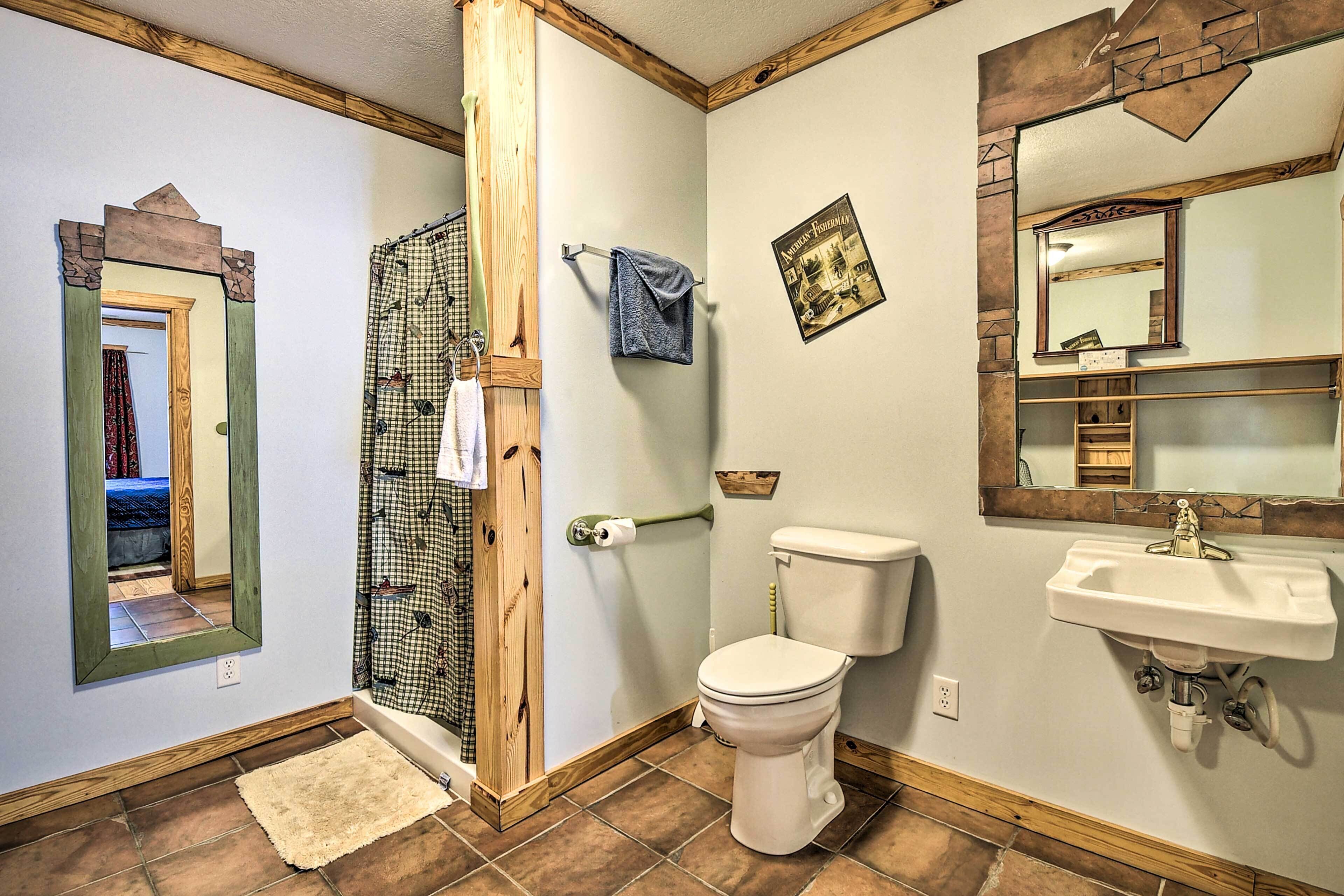 A bathroom with a shower, toilet, sink, and a mirror.