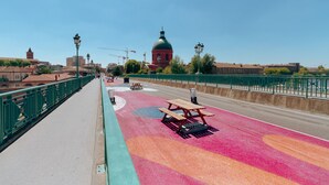 A pedestrian bridge with colorful pavement, benches, and a green railing. - Quiet 1-bed with office space, Saint-Cyprien, 200m to metro (Toulouse)