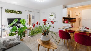 A modern living room with a sofa, a dining table with red chairs, a TV, and a kitchen area. - Quiet 1-bed with office space, Saint-Cyprien, 200m to metro (Toulouse)