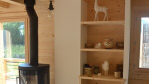 Tunnelmallinen huone, jossa on puukamiina, koriste-esineitä sisältäviä hyllyjä ja näkymä ulos.