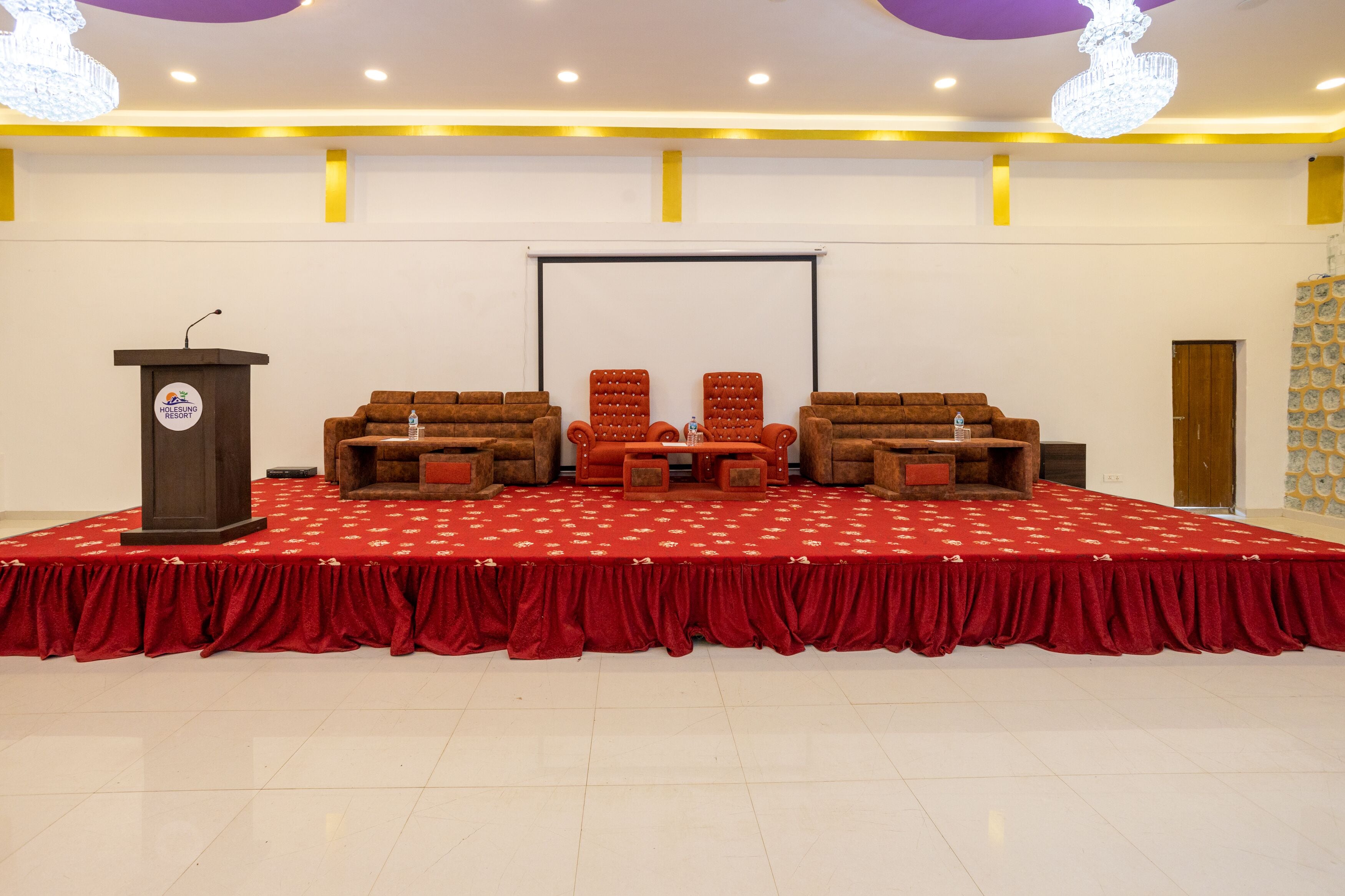 A stage with a podium, two red chairs, and a red carpet.