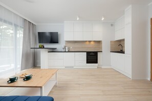 Une cuisine moderne avec des armoires blanches, un plan de travail en bois et un four encastré.
