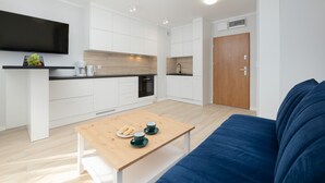 Une cuisine moderne avec des meubles blancs, un plan de travail en bois et un four encastré.