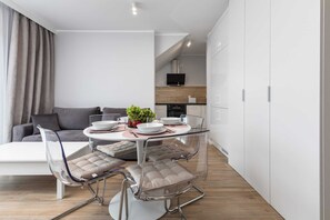 Una cocina moderna con armarios blancos, horno empotrado y televisor sobre la encimera.
