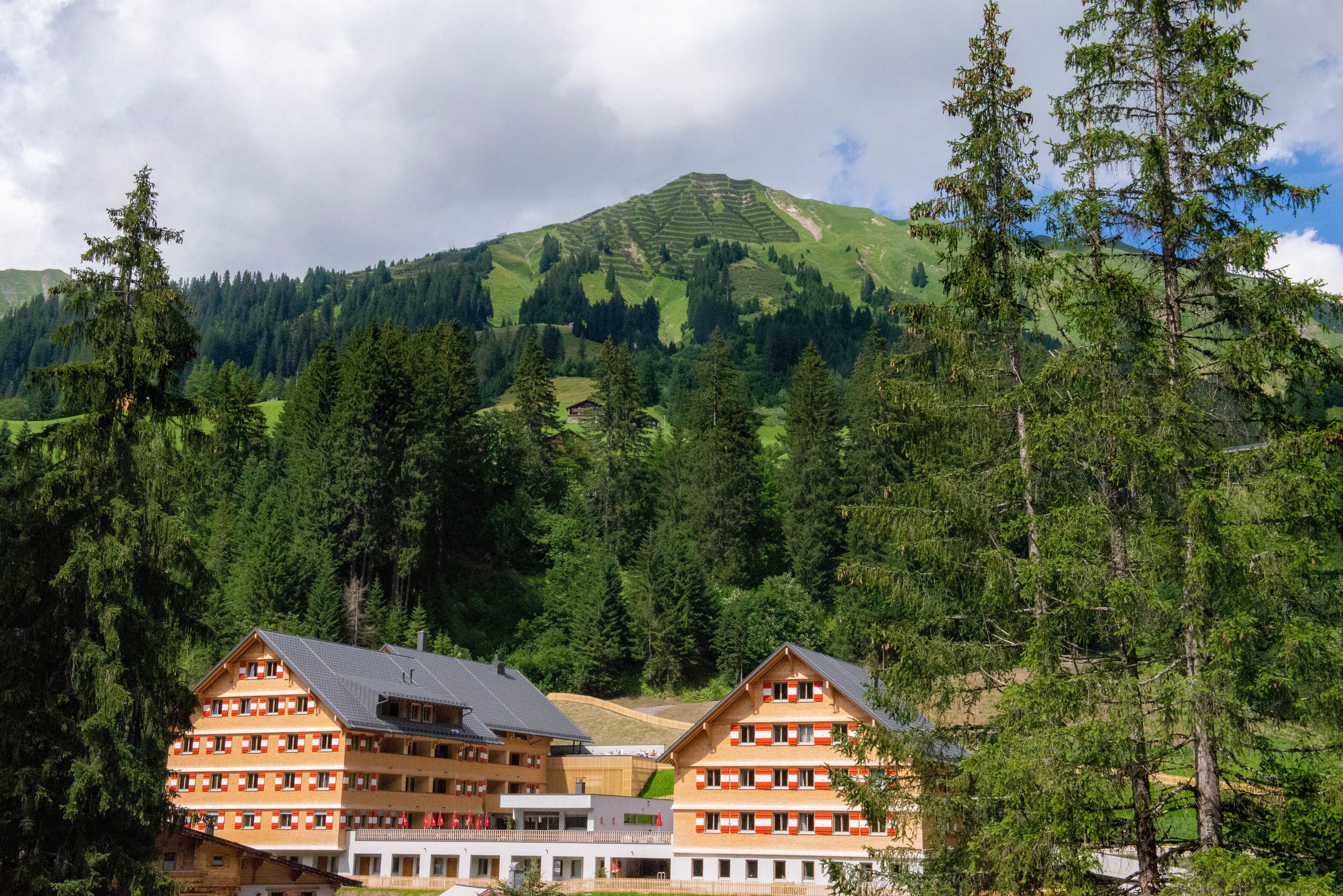 Un hôtel de style architectural alpin traditionnel, doté de nombreux balcons et offrant une vue imprenable sur les montagnes.