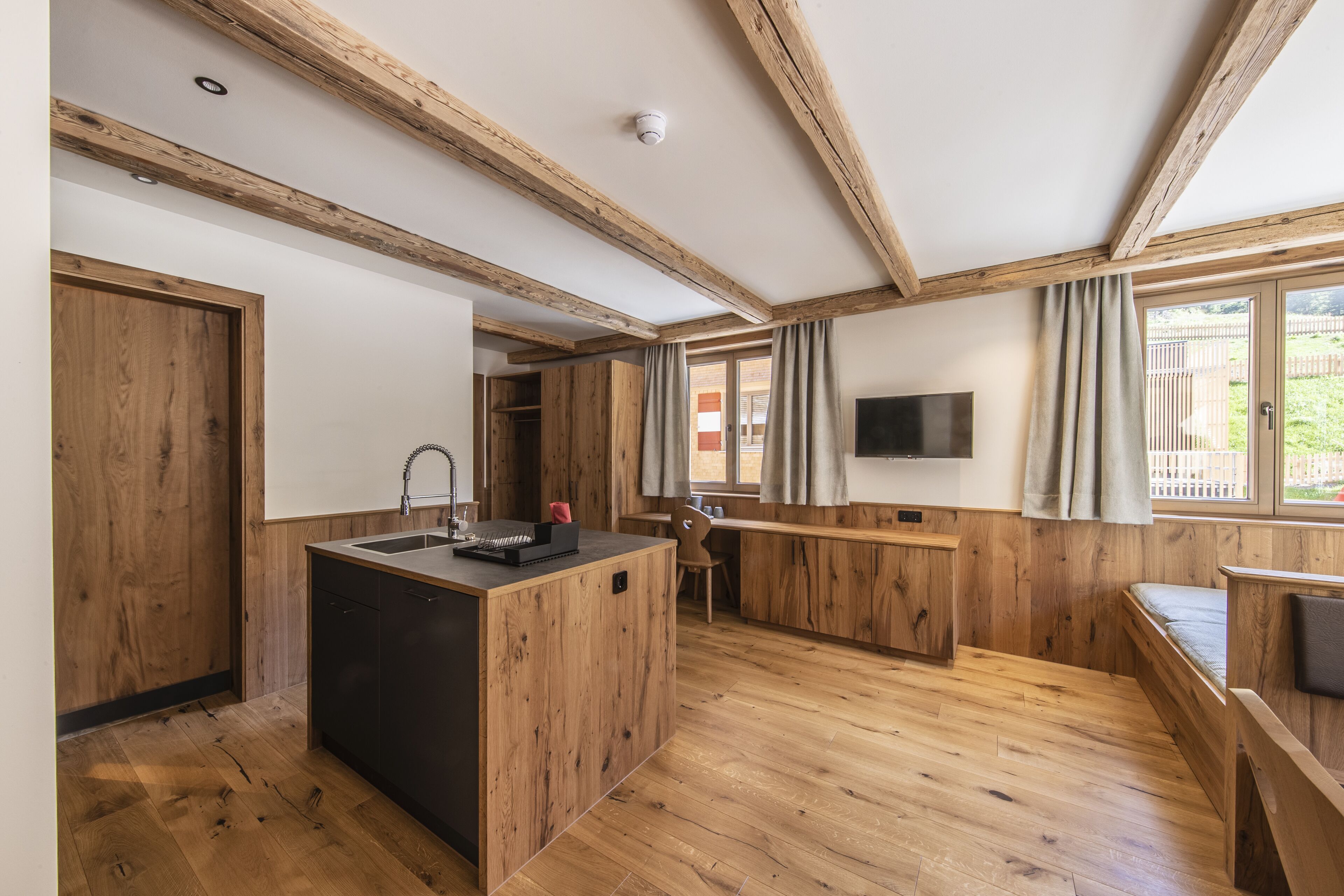 Una cocina moderna con vigas de madera, una isla central y un comedor con banco.