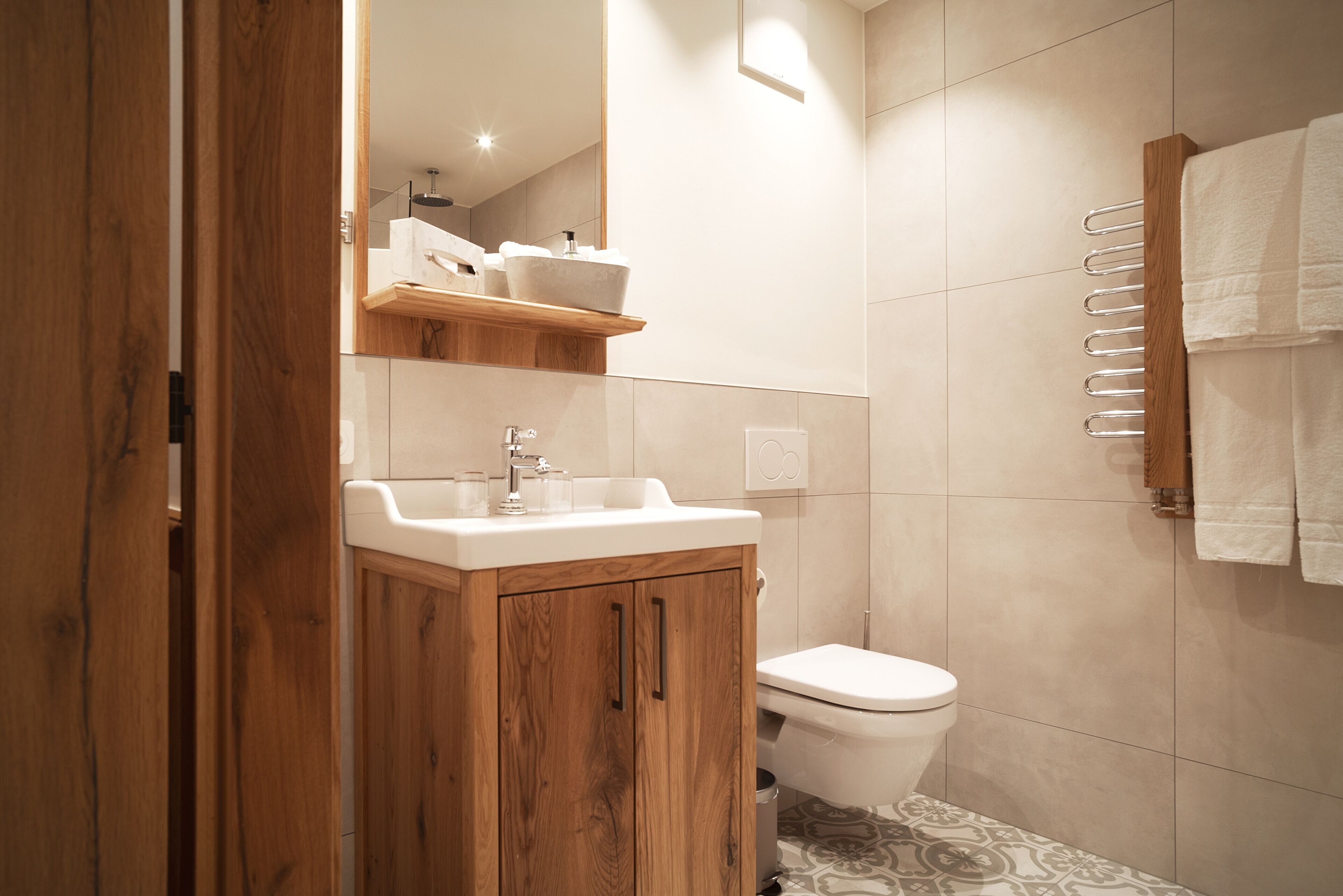 A modern bathroom with a wooden vanity, a toilet, and a towel rack.