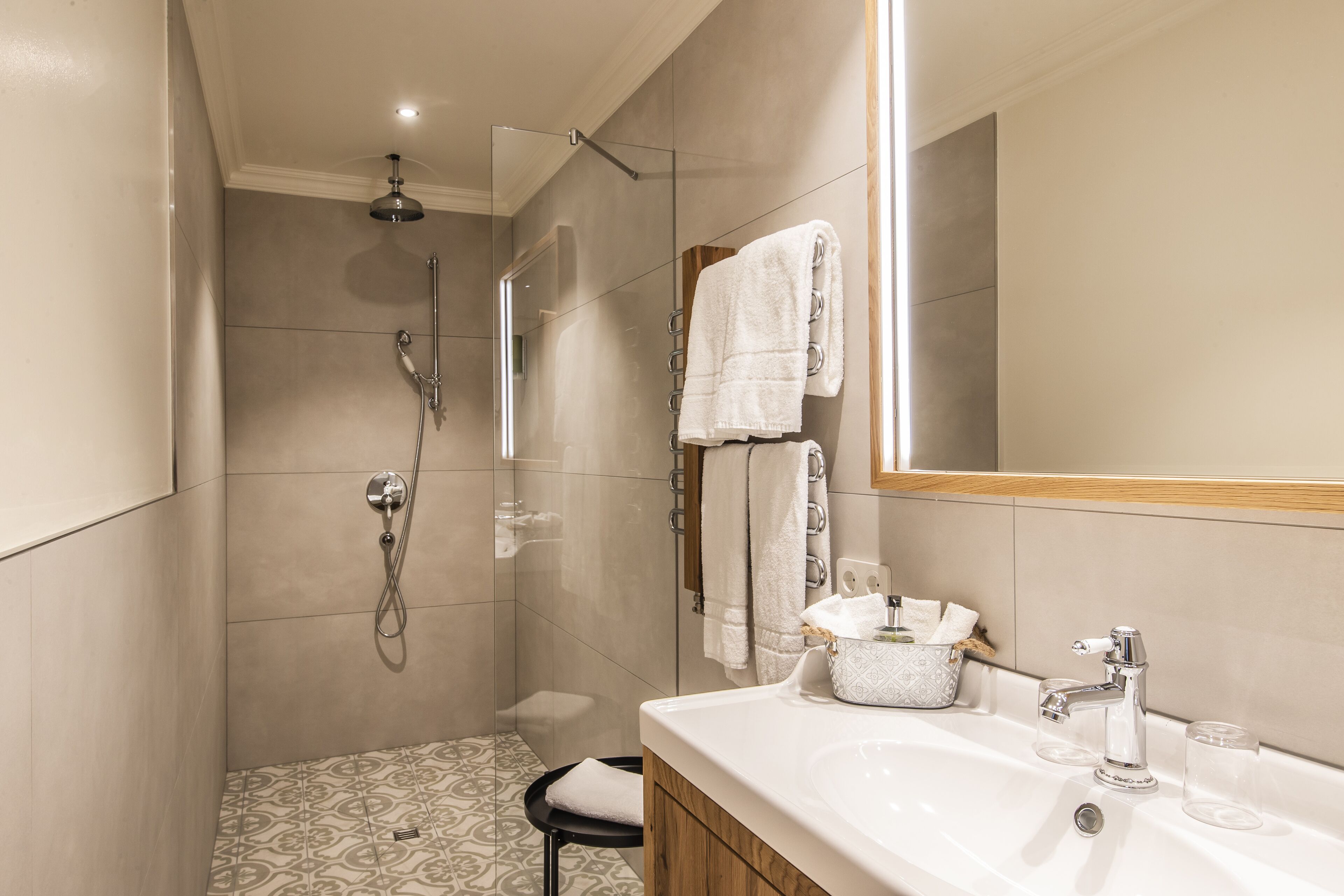 A modern bathroom with a glass-enclosed shower, a vanity with a sink, and a mirror.
