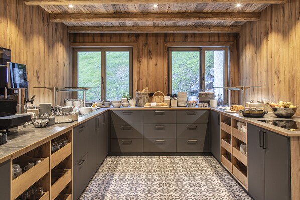 Una cocina con paredes de madera, piso de baldosas y un ventanal grande.