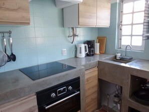 Enjoy cooking in this well-equipped kitchen with a black induction cooktop, oven, and stainless steel sink.