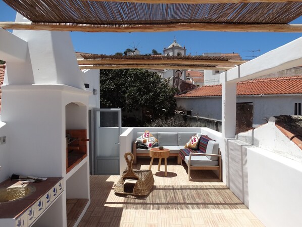 Relax on the rooftop with a comfortable seating area, sofa, and chairs, surrounded by a view of the neighborhood.
