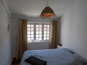 Cozy retreat with a single bed, large window, and unique light fixture.