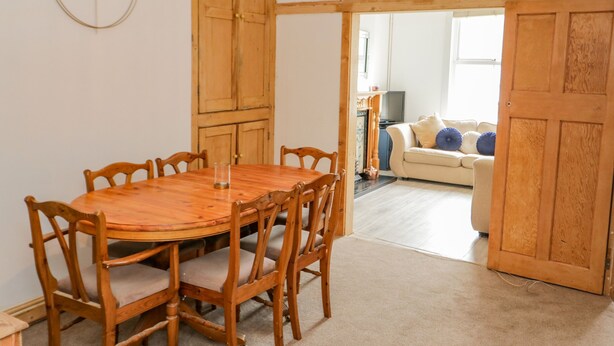 Un coin repas avec une table et des chaises en bois, une armoire en bois, et un salon avec un canapé et un téléviseur.