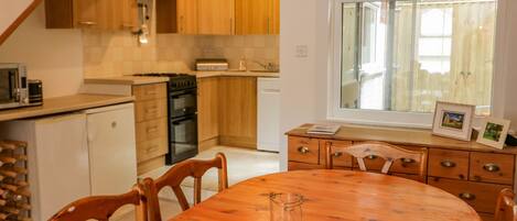 A kitchen with wooden cabinets, a stove, and a dining area with a wooden table and chairs.