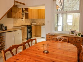 A kitchen with wooden cabinets, a stove, and a dining area with a wooden table and chairs.