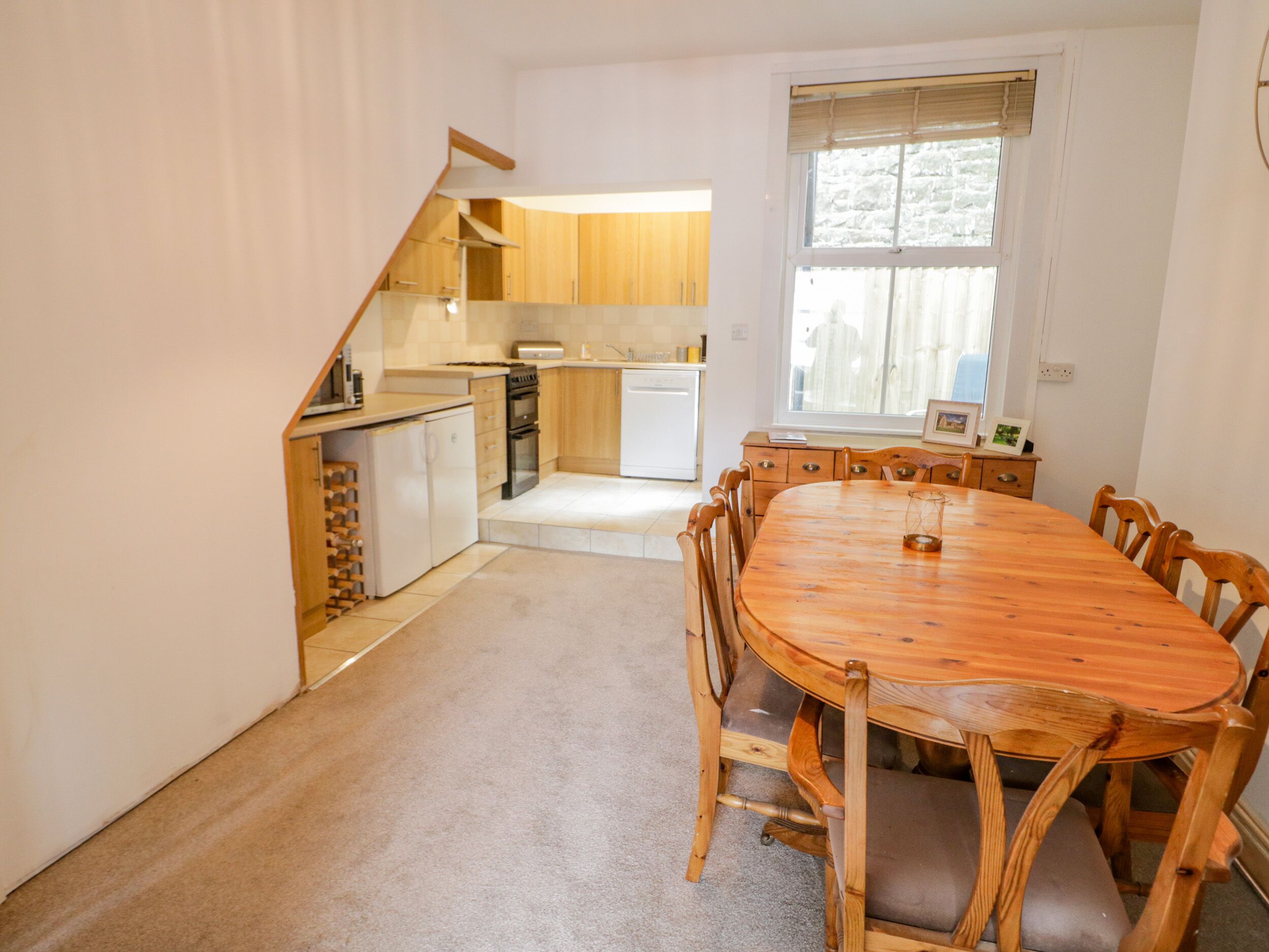Une cuisine compacte avec des meubles de rangement en bois, une table à manger avec des chaises et un petit réfrigérateur.