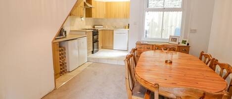 Una cocina compacta con armarios de madera, una mesa de comedor con sillas y un refrigerador pequeño.