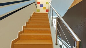 A staircase with a metal handrail and a colorful wall at the top. - Itsy Hotels Friends (Haldwani)