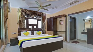 A hotel room with a bed, a ceiling fan, a wardrobe, and a door leading to another room. - Itsy Hotels Friends (Haldwani)